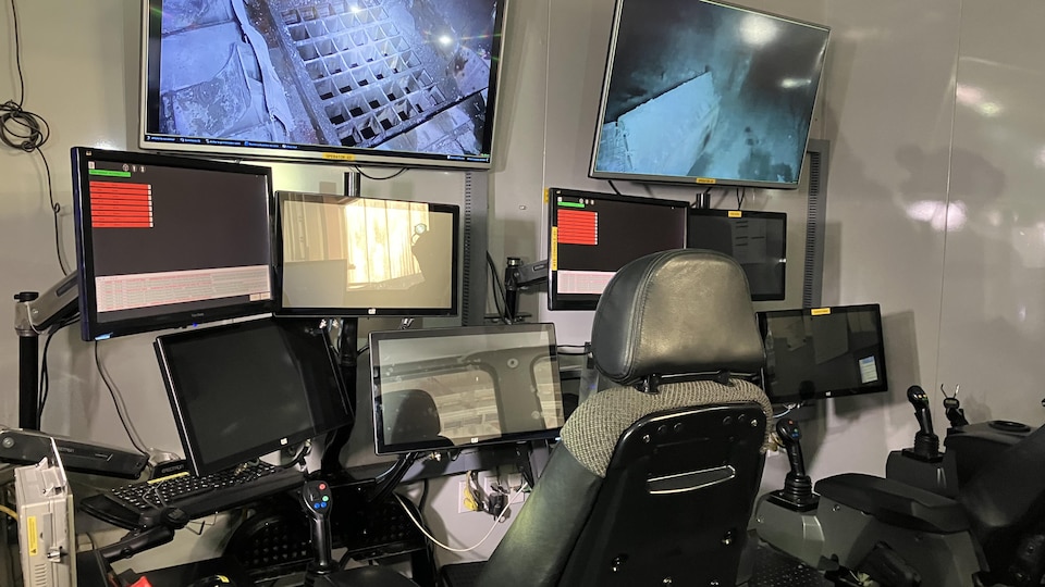 Une salle de contrôle avec des écrans, des sièges, des manettes et des ordinateurs.